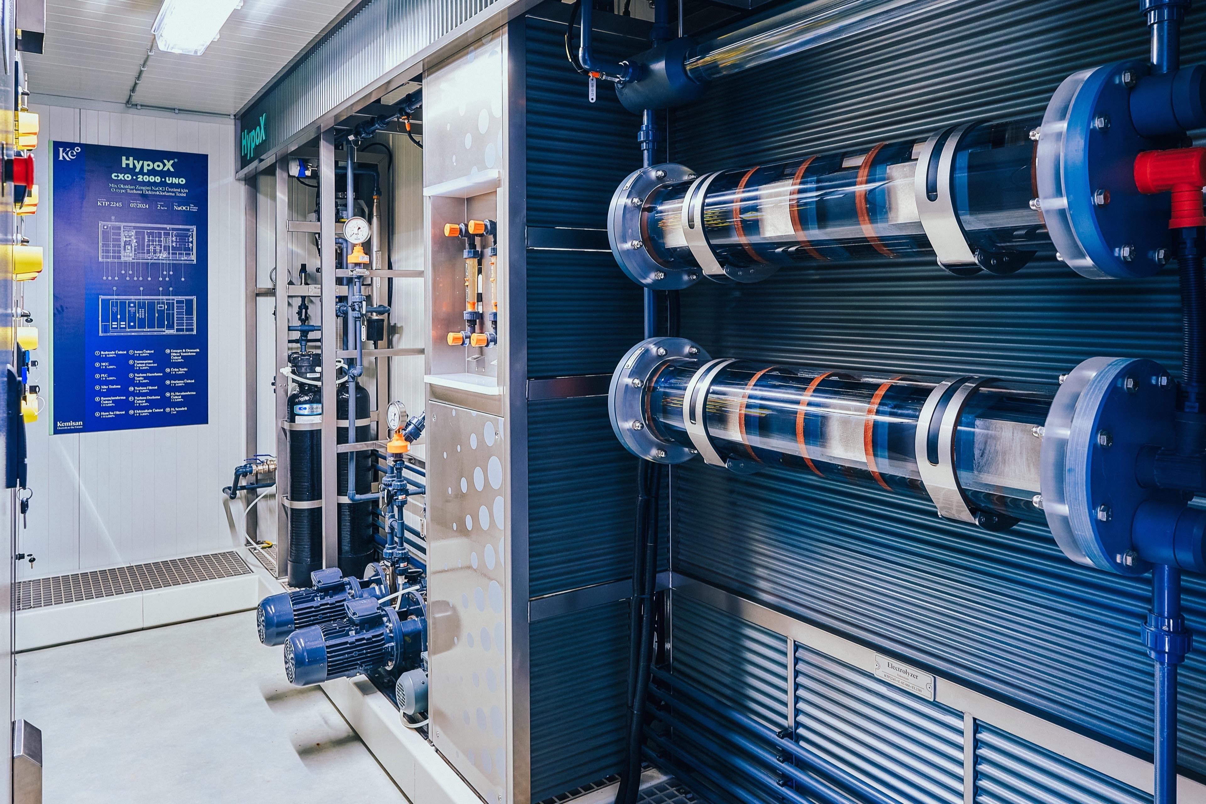 Interior of a HypoX CX container with electrolyzer cells, valves and a branded CXO·2000·UNO panel in a Kemisan production facility