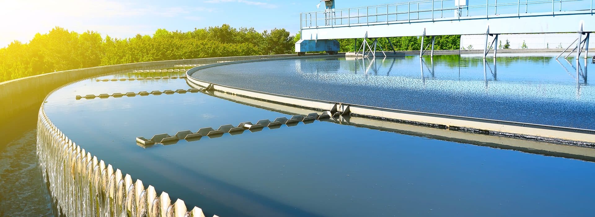 Sunlit circular water treatment tank with a rotating skimmer arm