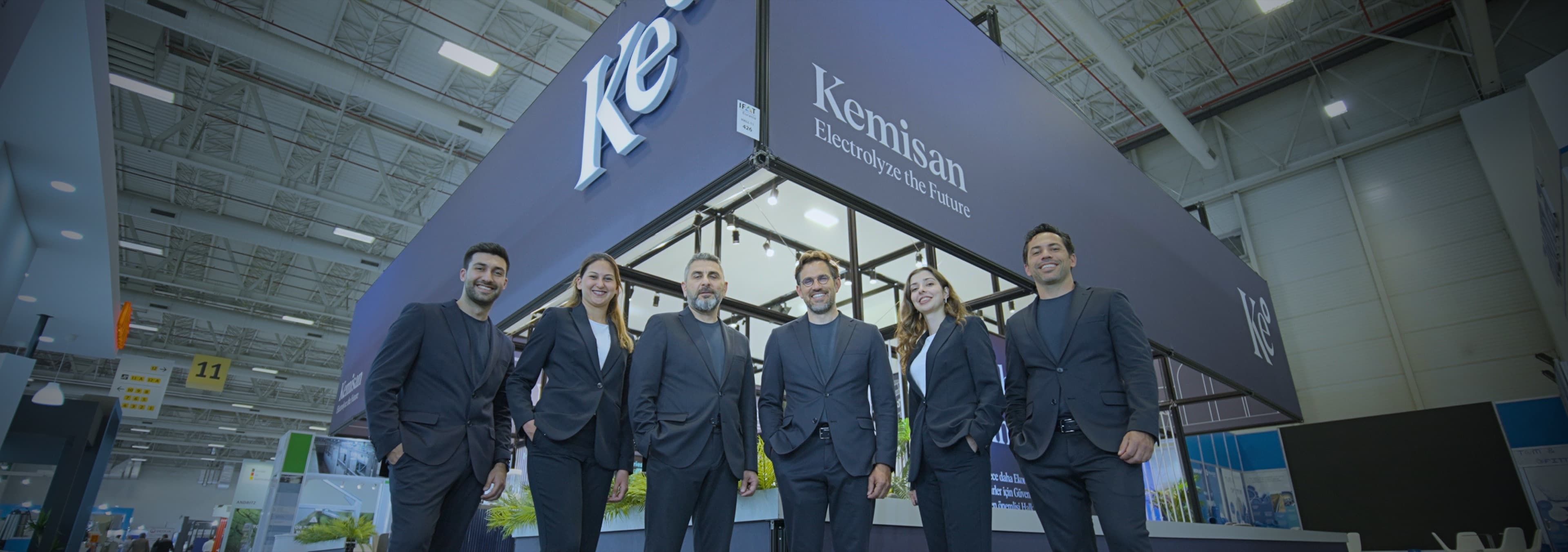 Kemisan team standing together under the Kemisan booth at the IFAT exhibition