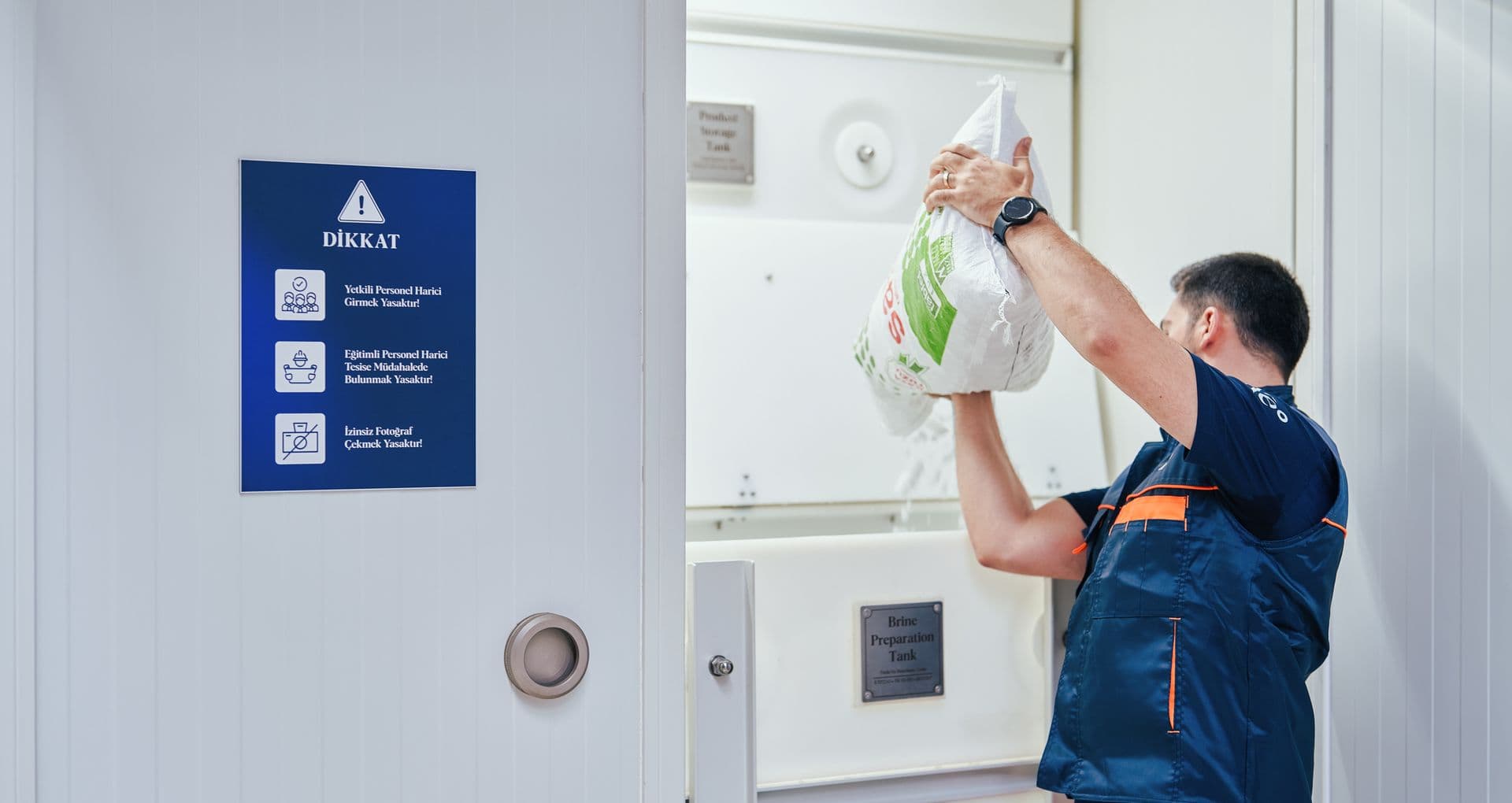 Kemisan technician loading a bag of salt into the brine preparation tank inside the container