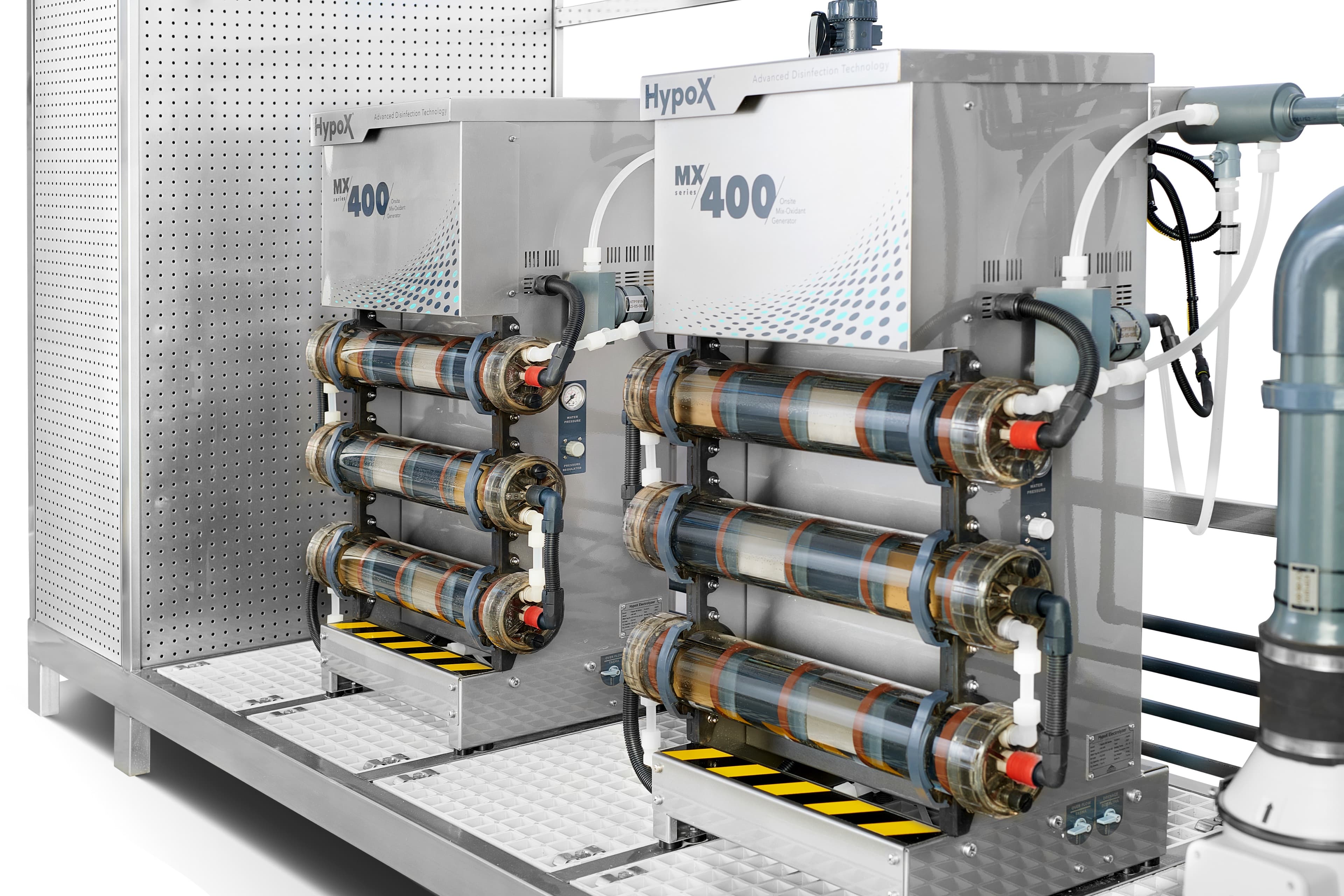 Close-up of a HypoX MX Series skid showing electrolyzer cell tubes, pumps, and pressure gauges
